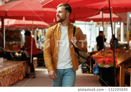 Front view, walking. Handsome man is on the street market or bazaar Front view, walking. Handsome man is on the street market or bazaar 132205695