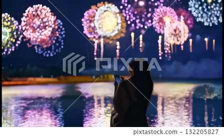 Fireworks reflected on the water surface and a woman taking a photo with her smartphone 132205827