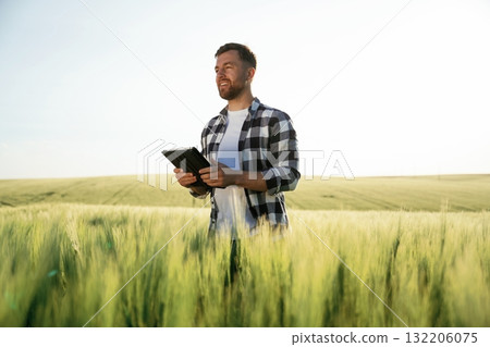 Digital tablet in hands. Handsome man is on the agricultural field at daytime 132206075