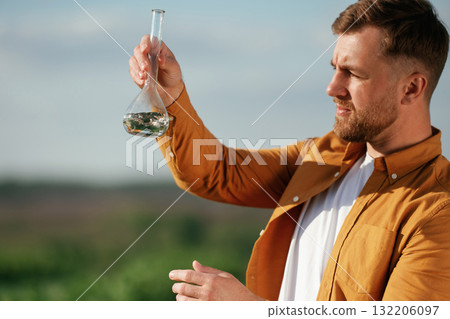 Scientific research, with test tube. Handsome man is on the agricultural field at daytime 132206097