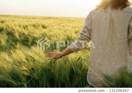 Touching the plants. Woman in white is on the agricultural wheat field Touching the plants. Woman in white is on the agricultural wheat field 132206267