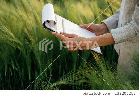 Reading the documents. Woman in white is on the agricultural wheat field Reading the documents. Woman in white is on the agricultural wheat field 132206295