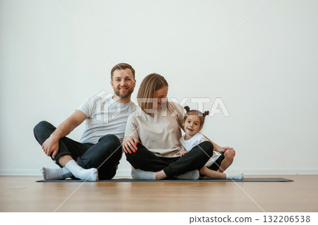 Cheerful people. Family of mother, father and daughter are doing yoga at home 132206538