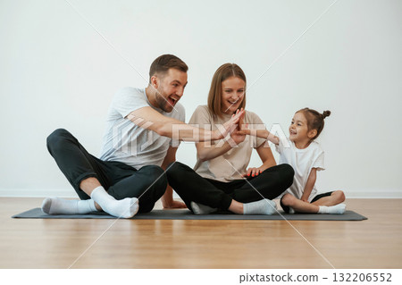 Doing high five. Family of mother, father and daughter are doing yoga at home Doing high five. Family of mother, father and daughter are doing yoga at home 132206552