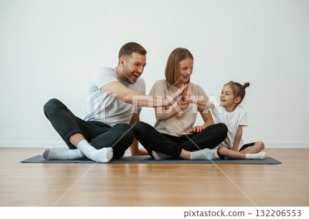 Doing high five. Family of mother, father and daughter are doing yoga at home Doing high five. Family of mother, father and daughter are doing yoga at home 132206553