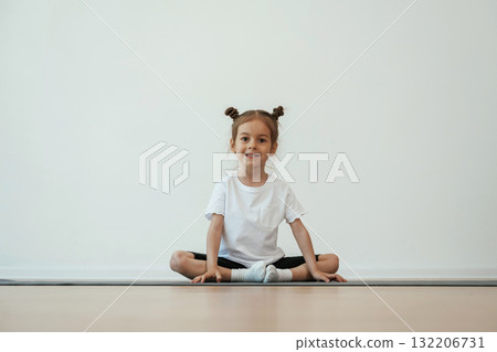 Cute little girl is sitting on the yoga mat and doing exercises Cute little girl is sitting on the yoga mat and doing exercises 132206731