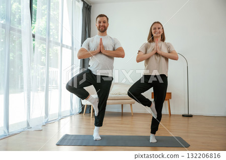 Man and woman are doing yoga exercises at home Man and woman are doing yoga exercises at home 132206816