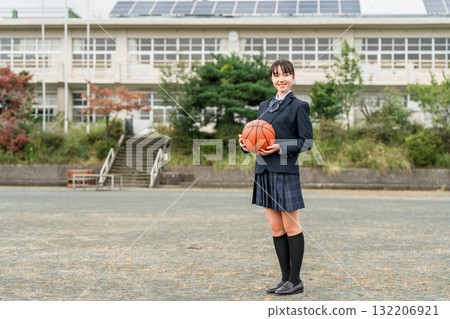 穿著校服的高中、國中和小學女生站在校園裡，手裡拿著籃球 132206921