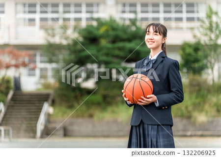 穿著校服的高中、國中和小學女生站在校園裡，手裡拿著籃球 132206925