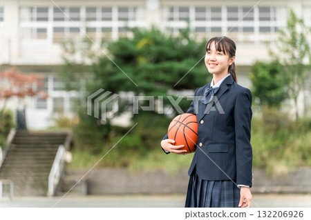 穿著校服的高中、國中和小學女生站在校園裡，手裡拿著籃球 132206926