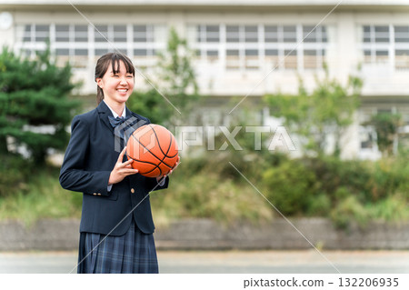 High school, junior high school, and elementary school girls in uniform standing in a schoolyard holding a basketball High school, junior high school, and elementary school girls in uniform standing in a schoolyard holding a basketball 132206935