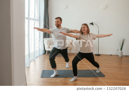 Warrior asana. Man and woman are doing yoga exercises at home 132207026