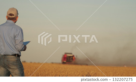 farmer working in wheat field, combine harvester ploughing in wheat field, agriculture tablet, digital tools for farmers, agricultural business strategies, field management via tablet, enhancing farmer working in wheat field, combine harvester ploughing in wheat field, agriculture tablet, digital tools for farmers, agricultural business strategies, field management via tablet, enhancing 132207275