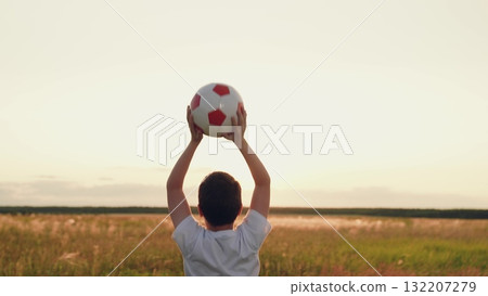 boy jumping up nature, child kid sunset, child victory, feeling victory, people ball, hands raised up sunny sky victory, back view boy holding ball in open field, boy holding soccer ball at sunset 132207279