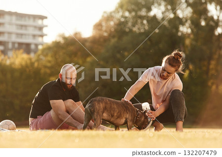 Giving the water. Man and woman are with dog on the field 132207479
