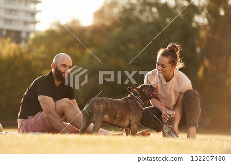 Man and woman are with dog on the field 132207480