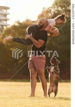 Girlfriend is with soccer ball. Man and woman are with dog on the field Girlfriend is with soccer ball. Man and woman are with dog on the field 132207492