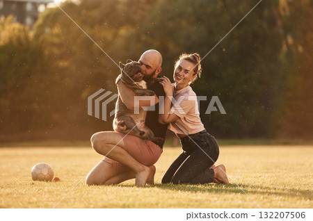 Positive facial expression, resting. Man and woman are with dog on the field Positive facial expression, resting. Man and woman are with dog on the field 132207506