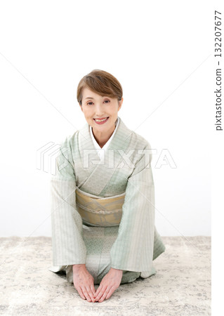 A woman in a kimono sitting upright bowing 132207677