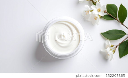 Top view of a cosmetic cream jar with green leaves on a white background with copy space. 132207865