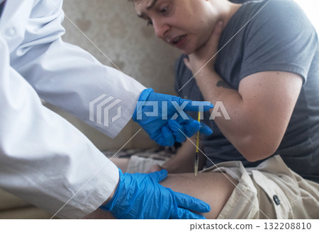 A man injects himself with adrenaline into his thigh during anaphylactic shock. First aid for allergies, emergency medical care for an allergic reaction. 132208810