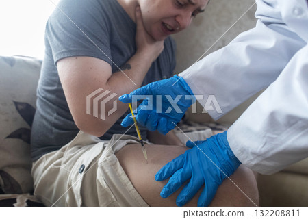 A man injects himself with adrenaline into his thigh during anaphylactic shock. First aid for allergies, emergency medical care for an allergic reaction. 132208811