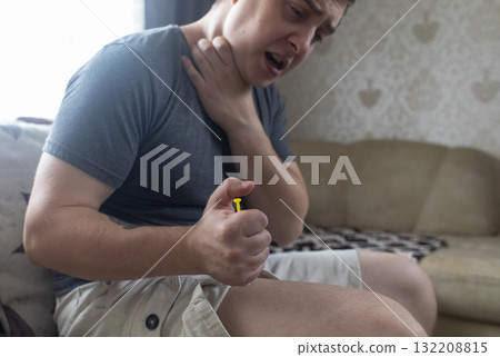 A man injects himself with adrenaline into his thigh during anaphylactic shock. First aid for allergies, emergency medical care for an allergic reaction. A man injects himself with adrenaline into his thigh during anaphylactic shock. First aid for allergies, emergency medical care for an allergic reaction. 132208815