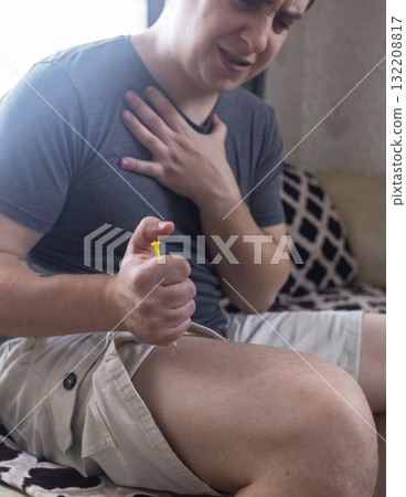 A man injects himself with adrenaline into his thigh during anaphylactic shock. First aid for allergies, emergency medical care for an allergic reaction. A man injects himself with adrenaline into his thigh during anaphylactic shock. First aid for allergies, emergency medical care for an allergic reaction. 132208817