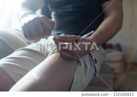 A man injects himself with adrenaline into his thigh during anaphylactic shock. First aid for allergies, emergency medical care for an allergic reaction. 132208823