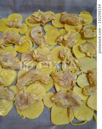 Raw chicken meat and sliced potatoes with spice marinade on baking tray Raw chicken meat and sliced potatoes with spice marinade on baking tray 132209154