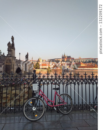 Prague, Czech republic - July 31, 2018: Pink bicycle rekola parked on charles bridge with prague castle in background during sunrise Prague, Czech republic - July 31, 2018: Pink bicycle rekola parked on charles bridge with prague castle in background during sunrise 132209172