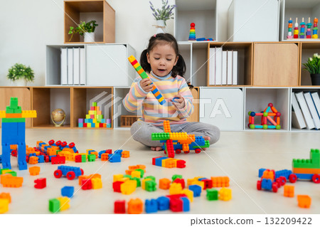 toddler girl playing building blocks or plastic bricks toy at home 132209422