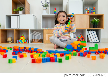 toddler girl playing building blocks or plastic bricks toy at home 132209423