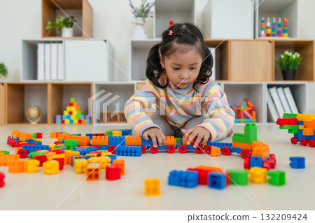 toddler girl playing building blocks or plastic bricks toy at home 132209424