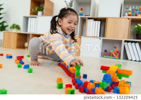toddler girl playing building blocks or plastic bricks toy at home 132209425