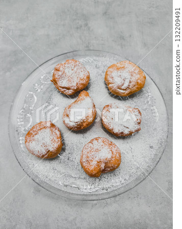 Delicious baursaki sprinkled with icing sugar on elegant glass plate in prague Delicious baursaki sprinkled with icing sugar on elegant glass plate in prague 132209491