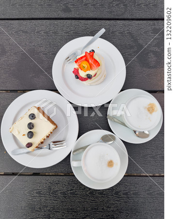 Delicious Carrot, meringue Pavlova cakes, and cappuccinos resting on a table in prague Delicious Carrot, meringue Pavlova cakes, and cappuccinos resting on a table in prague 132209602