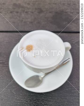 Creamy cappuccino resting on dark wooden table in prague Creamy cappuccino resting on dark wooden table in prague 132209610