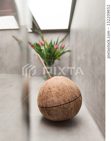 Coconut drink with straw near bouquet of tulips on kitchen counter 132209652