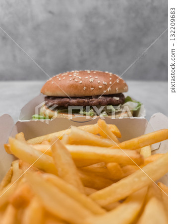 Hamburger with sesame seeds and french fries resting in cardboard containers galentines day 132209683