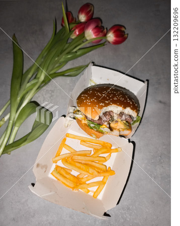 Cheeseburger and french fries with red tulips on gray table galentines day Cheeseburger and french fries with red tulips on gray table galentines day 132209696