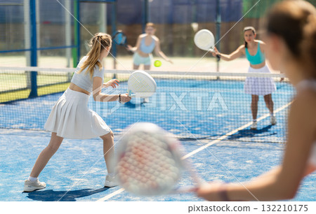 Young woman playing paddle tennis against team of women Young woman playing paddle tennis against team of women 132210175
