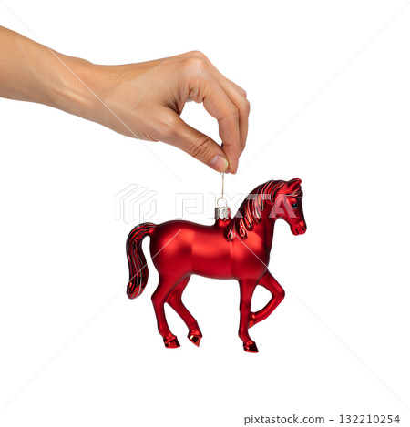 Hand holding classic red glass horse christmas ornament , festive holiday decoration isolated on a soft background Hand holding classic red glass horse christmas ornament , festive holiday decoration isolated on a soft background 132210254
