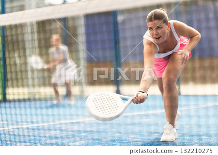 Young woman playing doubles padel tennis Young woman playing doubles padel tennis 132210275