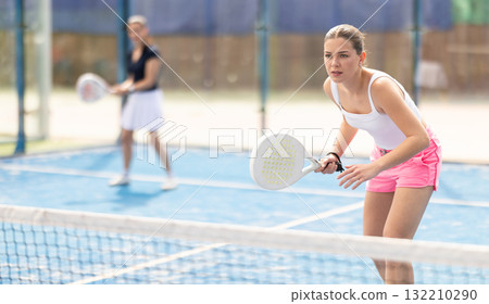 Woman standing behind net on tennis court Woman standing behind net on tennis court 132210290
