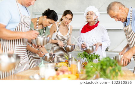 Amiable senior female chef running group culinary courses Amiable senior female chef running group culinary courses 132210856