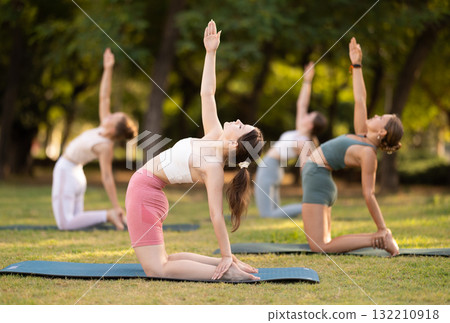 Yoga lesson visitors girls perform Ushtrasana in park 132210918
