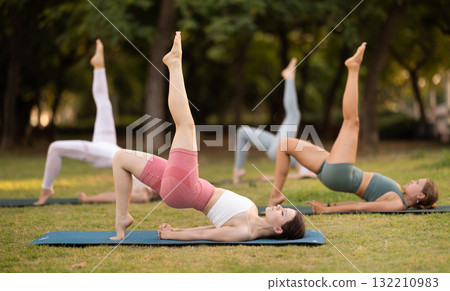 Yoga lesson visitors girls perform Setu Badha Sarvangasana in park Yoga lesson visitors girls perform Setu Badha Sarvangasana in park 132210983