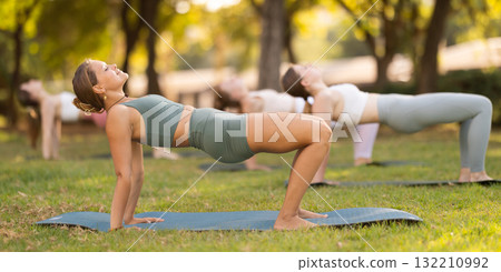 Yoga lesson visitors girls perform reverse plank in park Yoga lesson visitors girls perform reverse plank in park 132210992