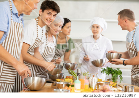 Young female cook teaches to cook group of people 132210997